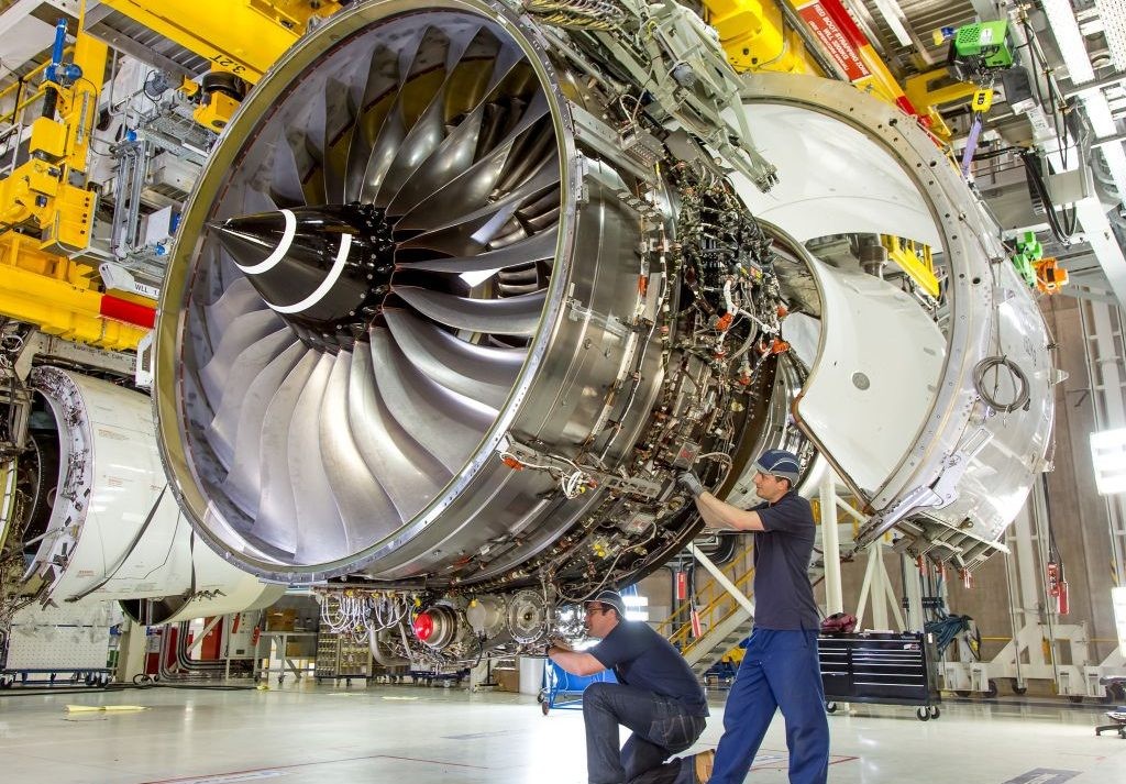 Technicians assembling a large commercial jet engine in a production hangar