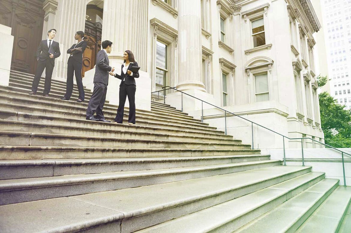 Professionals in conversation on the steps of a government building