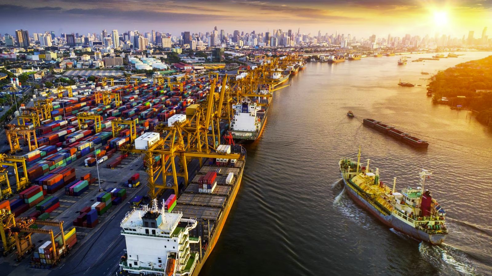 Aerial view of a container port with cranes and cargo ships at sunset