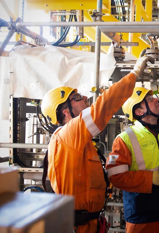 Technicians servicing pipework on an offshore platform