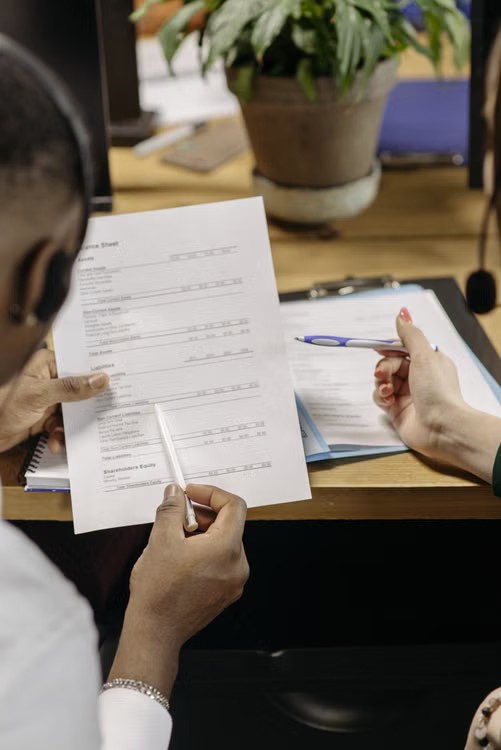 Two professionals reviewing a balance sheet during a financing discussion