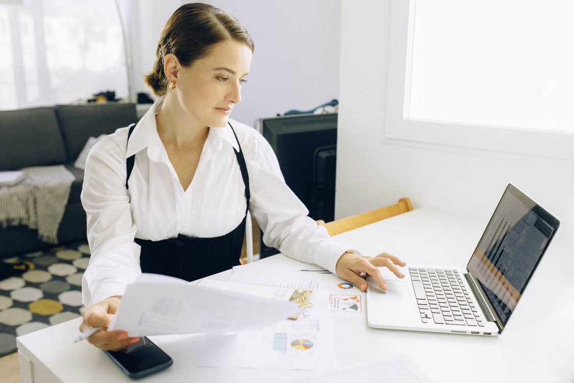 Finance professional reviewing reports at a laptop