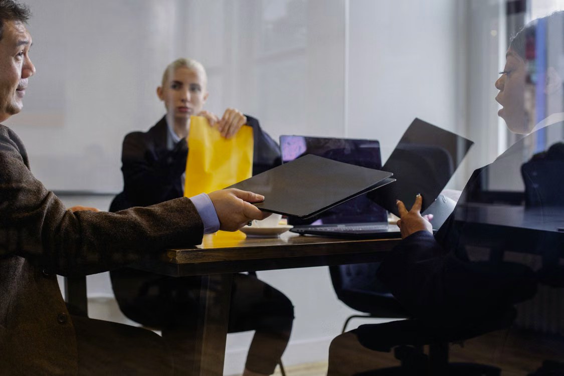 Business professionals exchanging documents across a conference table during a transaction